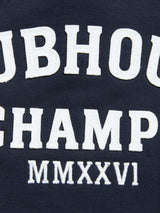 Close-up of navy blue cotton jersey fabric from the BGclubhouse Rugby Sweatshirt by Blue de Gênes, featuring large, bold white embroidered text reading “UBHOU CHAMP MMXXVI.” The classic lettering style evokes vintage athletic heritage, reminiscent of retro rugby sweatshirts.