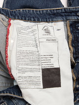 Close-up of the inside label of a pair of BGvinci Striker Jeans - Dark Distress by Blue de Gênes. The label includes text referencing Leonardo da Vinci, with both English and Italian language details. Red stitching is visible along the fabric seam. These regular fit jeans are made from comfort stretch denim, emphasizing their quality construction and modern comfort.