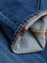 Close-up of the cuff on BGrepi Kanto Jeans - Used by Blue de Gênes, highlighting blue durable denim, folded fabric, visible orange stitching, and two small red stitches near the seam.