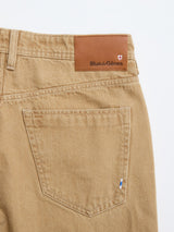 Close-up of the back pocket and belt area of Tanin BGgiacomo Color Jeans by Blue de Gênes, featuring a brown leather patch with the Blue de Gênes logo on the waistband.