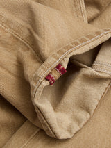 Close-up of light brown rigid denim fabric showing a seam with visible stitching and two small red bar tacks, likely the inside hem of a pair of relaxed loose fit BGgiacomo Color Jeans - Tanin by Blue de Gênes.