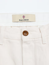 Close-up of the waistband of the BGpalco Twill Pants in Chalk by Blue de Gênes, featuring a brown button and a label above the waistband displaying the Blue de Gênes shield logo.