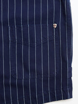 Close-up of the BGlumen Toll Gilet by Blue de Gênes in navy stripe, featuring white vertical pinstripes, a stitched pocket, and a small round badge with a red cross on white near the top right corner of the pocket.