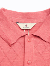 Close-up of the BGwally Diamond Polo in Coral by Blue de Gênes, featuring a diamond-knit pattern, three matching buttons, and a Blue de Gênes label.