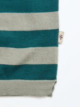 A close-up of the BGwally Stripe Polo - Shadow Green by Blue de Gênes reveals its premium cotton-linen knit, distinguished by green and beige horizontal stripes, a beige hem, and a small tag with a red cross on a white shield—showcasing timeless style and refined texture.