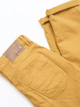 BGpaulo Pavia Pant - Sunflower by Blue de Gênes, folded on a white surface, features a back pocket and brown leather brand patch near the waistband. Made from soft cotton stretch fabric for comfort.