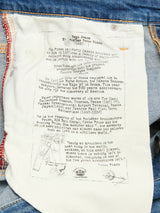 Close-up of the BGrepi Misto Jeans - Med Used by Blue de Gênes, showing a white inside pocket with printed text about architect Renzo Piano. Blue denim and orange stitching frame this unique style feature.