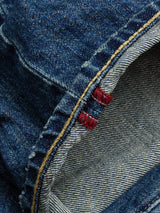 Close-up of BGgiacomo Tim Jeans - Antique wash by Blue de Gênes, featuring blue rigid denim with a visible seam finished in yellow stitching and two small red tags. The detailed fabric texture and the inner side highlight the jeans’ classic craftsmanship.