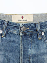 Close-up of BGgiacomo Tim Jeans - Antique wash by Blue de Gênes shows the waistband, button, belt loops, and label featuring a shield emblem—crafted from rigid denim and proudly made in Italy.