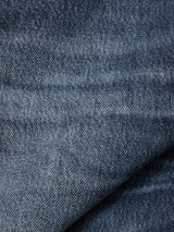 Close-up of blue denim fabric with a faded texture and visible weave pattern, showcasing natural creases and folds—hallmarks of the BGmarco Rowan Jeans - Used by Blue de Gênes.