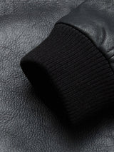 A close-up of a black ribbed knit cuff on a textured black leather sleeve, highlighting the refined details of the Blue de Gênes Rufo Shearling Jacket - Scarab.