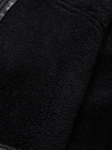 Close-up of the black, textured fabric of the Rufo Shearling Jacket - Scarab by Blue de Gênes, featuring a soft, fuzzy surface with visible seams characteristic of natural sheepskin.