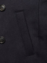Close-up of the Shiba Melton Coat - Dark Navy by Blue de Gênes, crafted from dark Italian Melton wool, featuring two black branded buttons and a horizontal rectangular slit pocket on the left side, showcasing refined Portuguese craftsmanship.
