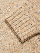 A close-up of the sleeve on the Blue de Gênes Honshu Crewneck Knit - Fungi highlights the beige, speckled lambswool blend yarn with a chunky knit texture and ribbed cuff, showcasing its multicolored details.