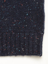 Close-up of the Honshu Crewneck Knit in Navy by Blue de Gênes, crafted from a lambswool blend knitted fabric with multicolored flecks in red, white, and blue. The bottom edge showcases a classic ribbed hem, evoking the traditional crewneck sweater style, while the right edge retains a natural, unfinished appearance. Set against a white background.