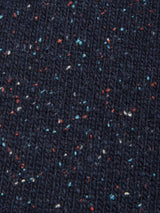 Close-up of the Honshu Crewneck Knit - Navy by Blue de Gênes, featuring dark blue knitted fabric with small multicolored specks of red, white, and blue. The textured and cozy appearance, crafted from a soft lambswool blend, makes it perfect for a chunky knit crewneck sweater.