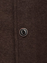 Close-up of a single brown button sewn onto textured, dark brown boiled wool fabric from the Blue de Gênes Kojima Wool Jacket - Chocolate.
