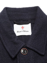 Close-up of the Kojima Wool Jacket - Navy collar by Blue de Gênes, featuring a single button and an inner white label with the brand’s name and a red cross emblem.