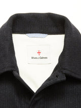 Close-up of the Vincenzo Solid Jacket - Dark Navy by Blue de Gênes: this relaxed fit features a dark collar, white inner lining, signature label with red shield, and a hint of blue-and-white striped fabric at the neckline.