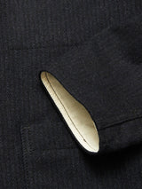 Close-up of the Blue de Gênes Vincenzo Solid Jacket - Dark Navy, highlighting its textured black fabric, visible pocket, and cream inner lining peeking from the pocket opening.