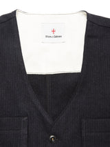 Close-up of the Maurice Solid Gilet - Dark Navy by Blue de Gênes, a tailored layering vest featuring two chest pockets and an inside collar label displaying the brand’s name beneath a small red and white emblem.