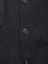 Close-up of a dark textured fabric coat with three black buttons and two pockets, layered over the Blue de Gênes Maurice Solid Gilet in Dark Navy for added tailored sophistication.