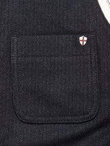 Close-up of a dark fabric pocket on the Maurice Solid Gilet - Dark Navy by Blue de Gênes, featuring a small shield-shaped pin with a red cross on white, attached to the upper right corner of this tailored layering vest.