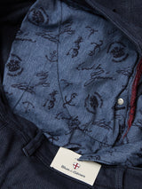 Close-up of the inner lining of navy Menzo Olanda Chino cotton blend chinos by Blue de Gênes, featuring a patterned blue fabric with handwritten-style text, symbols, and a visible Blue de Gênes tag at the bottom.