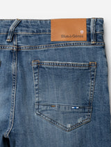 Close-up of BGvinci Girisha Used Jeans by Blue de Gênes, featuring blue comfort stretch denim, a brown leather Blue de Gênes patch on the waistband, back pocket detail, and intricate stitching.