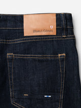 Close-up of the back pocket of BGvinci Girisha Rinse Jeans - Rinse Wash by Blue de Gênes, showing yellow stitching, a tan leather Blue de Gênes patch, small shield logo, and classic five-pocket design.