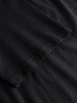 A close-up of a BGoscar T-Shirt - Jet Black sleeve by Blue de Gênes, resting on matching black fabric, highlights the stitching detail and distinctive texture of its 100% slub cotton.
