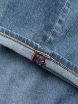 Close-up of Blue de Gênes BGvinci Pala Used V2 Jeans in denim blue, made in Italy, featuring a folded cuff with orange stitching and two red vertical threads on the comfort stretch inner seam.