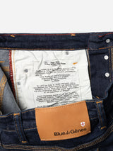 Close-up of the inside waistband of BGrepi Dai V Dark V2 Jeans in dark blue denim, showing a white fabric patch with printed text and a tan leather Blue de Gênes tag featuring a small red and white logo on the back.