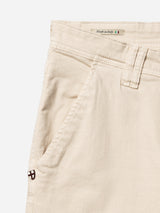 Close-up of the BGpaulo Pavia 1 V2 Chino - Ecru by Blue de Gênes, crafted from beige cotton stretch fabric and featuring a side pocket, belt loop, and a Made in Italy label adorned with an Italian flag. A small brown emblem is stitched near the pocket as a nod to classic vintage military chinos, highlighting these men’s durable pants designed for everyday wear.
