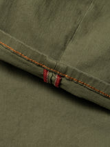 A close-up of olive green cotton stretch fabric with brown and two parallel red stitches on a folded hem, likely from Blue de Gênes' BGpaulo Pavia 1 V2 Chino - Army, inspired by vintage military pants.