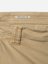 Close-up of khaki cotton stretch fabric pants from Blue de Gênes, the BGpaulo Pavia 1 V2 Chino, showing a waistband with a “Made in Italy” label and the Italian flag. A visible belt loop with orange stitching highlights the refined craftsmanship inspired by vintage military pants.