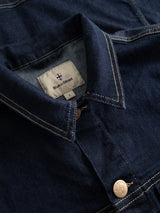 Close-up of a dark blue BGcosimo Trucker V2 Jacket by Blue de Gênes, featuring western denim style, tan stitching, metallic buttons, and an inner collar label with the brand's shield logo.