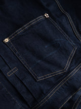 Close-up of the BGcosimo Trucker V2 Jacket by Blue de Gênes in dark blue denim, showing its classic western style, contrasting yellow stitching, and a small pin with a red cross on white displayed on the back pocket.