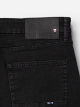 Close-up of the BGvinci TrueBlack Jeans’ back pocket and waistband, showcasing a leather patch labeled Blue de Gênes and a small red and white shield logo. These regular fit jeans also feature a small blue, white, and red accent above the pocket, and are crafted from comfort stretch black denim for ease of movement.
