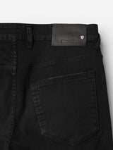 Close-up of the back pocket on the BGrepi TrueBlack Jeans – Black Denim by Blue de Gênes, featuring a black leather patch with embossed brand text and a small red and white shield emblem, highlighting high-quality craftsmanship.