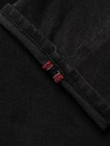 Close-up of a folded hem on the BGrepi TrueBlack Jeans by Blue de Gênes, crafted from black comfort stretch denim. The visible selvedge edge shows two narrow red lines, highlighting the durable fabric’s stitching and texture.