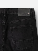 Close-up of the back pocket area of the BGmarco Connor Jeans - Black Denim Used by Blue de Gênes, crafted from 100% cotton denim. The image highlights a black leather patch embossed with the Marco Used Jeans logo and a small red and white shield emblem on the waistband. The relaxed fit guarantees comfort and timeless style.
