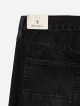 A close-up of the BGmarco Connor Jeans - Black Denim Used by Blue de Gênes, featuring a label with the brand name on the waistband, and showcasing the back pocket along with contrast stitching on 100% cotton denim.