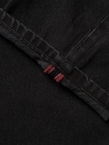 Close-up of black 100% cotton denim fabric from the BGmarco Connor Jeans - Black Denim Used by Blue de Gênes, featuring a seam and a small section of red and white selvedge edge visible beneath the folded hem.