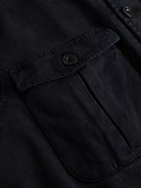 Close-up of the BGbarnaba Iro Overshirt by Blue de Gênes in navy, featuring a button-flap pocket that highlights precise stitching and the soft texture of its lyocell-cotton blend, reflecting a workwear-inspired design.