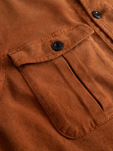 Close-up of the BGbarnaba Iro Overshirt in Ginger Bread Orange by Blue de Gênes, featuring a visible flap pocket with a black button. The gently raised pocket flap highlights the precise stitching and showcases the soft comfort fabric and textured finish of this workwear-inspired piece.