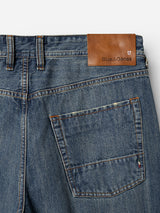 Close-up of BGgiacomo Alfie Jeans in mid blue denim, crafted from comfort stretch fabric, featuring a back pocket and a brown leather patch with the Blue de Gênes brand name stitched above the pocket.