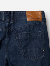 Close-up of the BGgiacomo Arthour Jeans in Denim Blue from Blue de Gênes, highlighting a back pocket and a brown leather patch embossed with the Blue de Gênes name and emblem near the waistband.