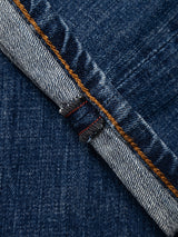 Close-up of the Blue de Gênes BGrepi Callum Jeans in Mid Blue Denim, showcasing a selvedge edge with visible orange stitching and a distinct red line that highlights the textured fabric and detailed seam. Crafted from comfort stretch denim, these regular slim fit jeans combine durability with everyday ease.
