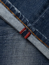 Close-up of the BGvinci OM Jeans - Denim wash by Blue de Gênes, featuring a blue selvedge denim edge with distinctive red stitching and contrasting orange thread along the seam, highlighting the authentic worn-in wash and regular fit of these jeans.